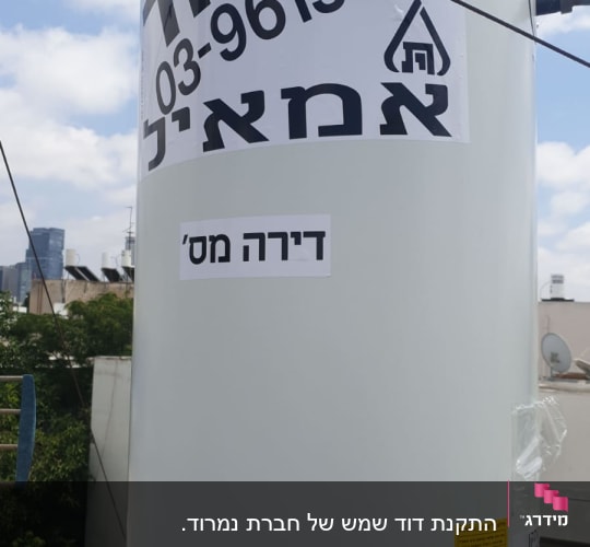 דוד שמש עם מדבקות טקסט בעברית על גג